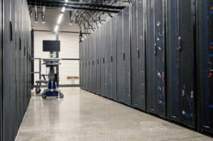 Interior of a modern data center with rows of server racks, overhead cabling, and a clean aisle designed for high-capacity power and cooling infrastructure.