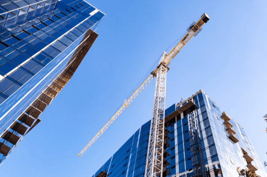 Construction crane between two modern glass office buildings during urban redevelopment project